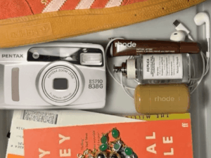 A lifestyle flat lay featuring a Pentax Espio 838G compact camera, representing the comeback of compact cameras and a digital detox lifestyle.