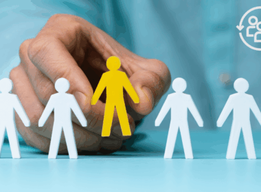 A hand selecting a specific yellow figure among white silhouettes, representing the importance of ICP definition before starting Email, LinkedIn, or ABM campaigns.