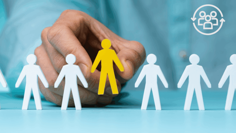 A hand selecting a specific yellow figure among white silhouettes, representing the importance of ICP definition before starting Email, LinkedIn, or ABM campaigns.