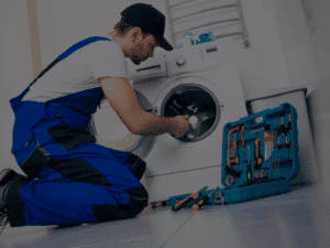 A professional technician repairing a washing machine with a toolkit, illustrating how appliance repair services can save you money by extending equipment lifespan.