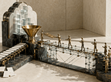 A brass sculpture contrasts blank content cards on a conveyor with people passing a detailed document across a glass bridge.